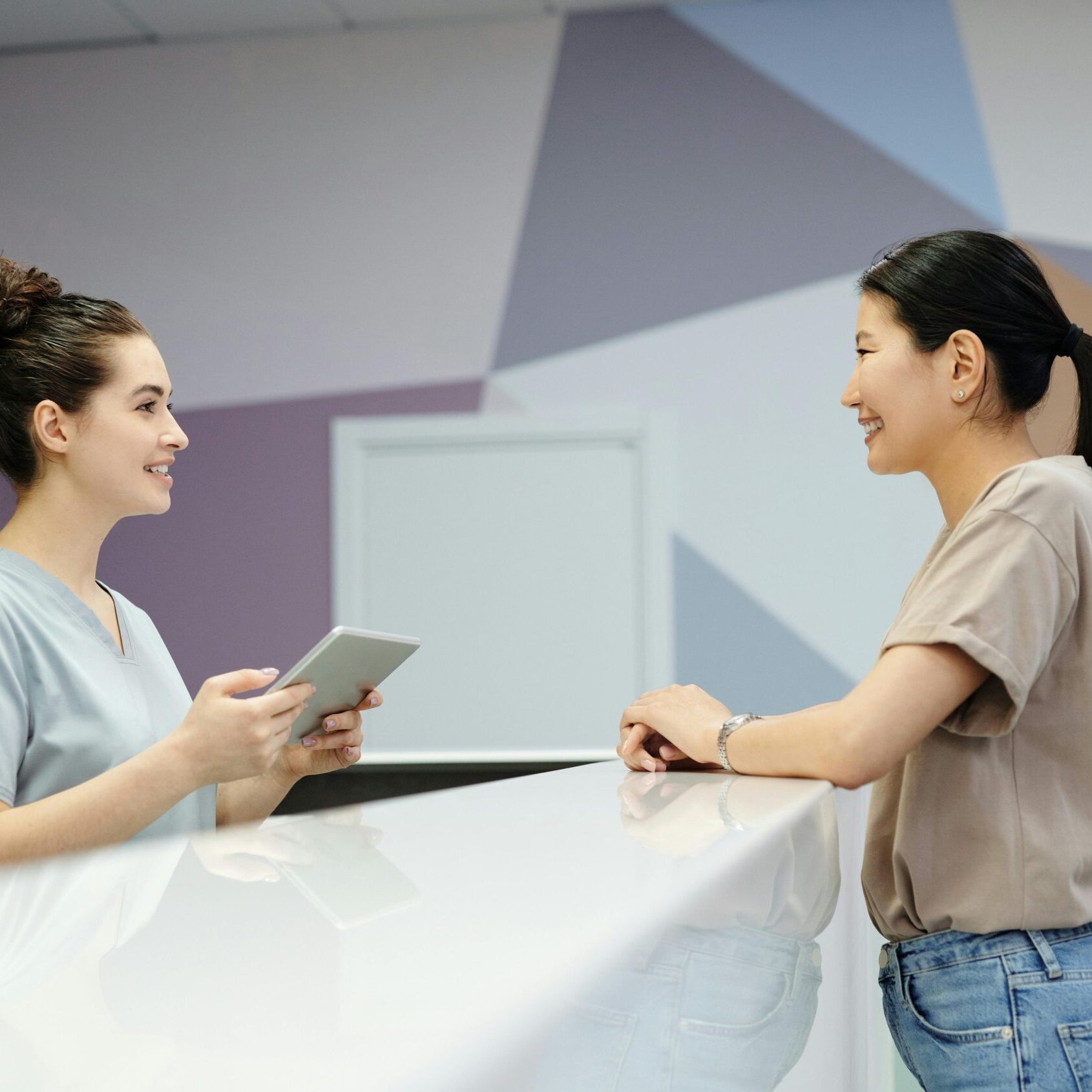 A receptionist and a visitor engaging at a modern reception desk, indoors.
